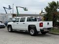 A white 2016 GMC Sierra 1500 pickup truck is parked with its rear facing the viewer featuring a crew cab design and chrome wheels