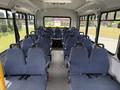 Interior of a 2017 Chevrolet Express shuttle bus featuring rows of blue fabric seats with seatbelts and aisle in the center