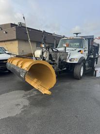 A 2007 International 7300 with a yellow snow plow attached in the front