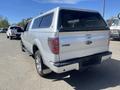 A silver 2014 Ford F-150 pickup truck with a canopy on the bed viewed from the rear angle showing the tailgate and back of the cab