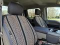 Two front seats of a 2018 Ford F-150 featuring patterned seat covers and a center console with cup holders