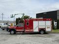 A 2007 Ford F-550 fire rescue truck painted red with emergency markings and equipment compartments on the side