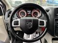 Interior view of a 2017 Dodge Grand Caravan featuring a black steering wheel with controls and a digital display dashboard with red accents