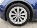 Close-up of a silver alloy wheel with a Tesla emblem on a blue 2020 Tesla Model X