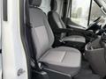 The interior of a 2023 Ford Transit displaying two gray seats with a textured pattern and a steering wheel in the foreground