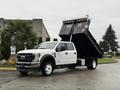 A white 2022 Ford F-550 dump truck with an elevated bed for unloading cargo