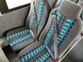 Interior seats of a 2022 Blue Bird BB Conventional bus featuring gray upholstery with blue and turquoise patterns and adjustable seatbelts