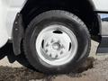 A close-up of a 2021 Ford Econoline wheel featuring a white rim with multiple lug nut holes and a sturdy black tire with visible tread patterns