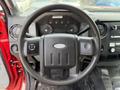 Steering wheel of a 2013 Ford F-550 with controls on the side and dashboard gauges visible in the background