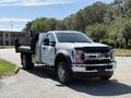 A 2019 Ford F-550 truck with a flatbed design in front view showcasing its chrome grille and large wheels