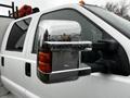 A 2014 Ford F-550 with chrome side mirror reflecting raindrops and a red light on the roof