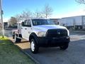 A white 2014 RAM 5500 flatbed truck with a black front grille parked on a street featuring a cab with a large cargo bed