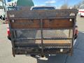 A 2013 Ford F-250 SD truck with a rusty flatbed and a metal mesh gate in the lowered position