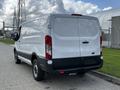 A white 2018 Ford Transit van viewed from the rear showing its sliding side door and taillights