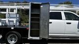 A white 2019 RAM 3500 truck with an open metal toolbox mounted on the side showing several shelves inside