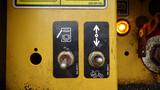 A yellow control panel with two levers labeled with symbols for operation and a small orange indicator light