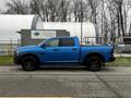 A blue 2021 RAM 1500 Classic pickup truck with a crew cab and black wheels parked on a driveway