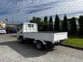 A 2004 Toyota Toyoace white truck with a flatbed and dual rear wheels parked on a concrete surface