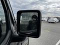 A close-up of the side mirror of a 2019 Jeep Wrangler showing a reflection of the driver and surrounding vehicles