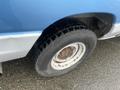 A close-up view of the wheel and tire of a blue and white 2009 Ford Econoline van showing a rugged tire tread and a white rim