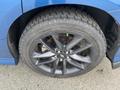 Close-up of a black alloy wheel on a blue 2022 Dodge Charger showcasing a detailed tire tread design and brake caliper