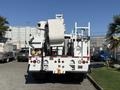 A white 2010 International 4300 bucket truck with a raised lift mechanism and rear-mounted equipment