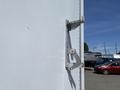 A silver door latch attached to a white truck trailer door