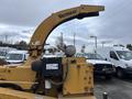 A yellow 2015 Vermeer Corporation BC1200XL wood chipper with a curved discharge chute and control panel visible in the foreground