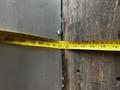 A close-up view of a tape measure extending across a wooden surface with markings showing centimeters and inches