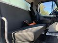 A black bench seat inside a 2017 Freightliner M2 106 with seat belts and a driver's seat positioned beside it
