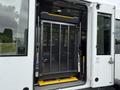 A 2020 Chevrolet Express with an open side door revealing a hydraulic lift platform for accessibility purposes