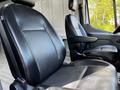Interior view of a 2021 Ford Transit driver's and passenger's seat featuring black leather upholstery and adjustable armrests