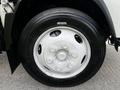 Close up of a white wheel rim with a shiny finish on a 2016 Isuzu NQR showcasing evenly spaced lug nuts and a smooth tire surface