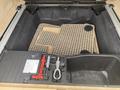 A 2009 BMW X5's trunk with a rubber mat and storage compartments for tools and a spare tire