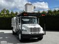 A white 2012 Freightliner M2 106 truck with a black flatbed and an elevated platform at the rear for equipment storage