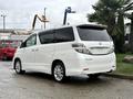 A 2009 Toyota Vellfire in white with a sleek design featuring large windows and chrome accents parked on a concrete surface
