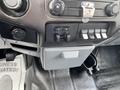 Interior dashboard controls of a 2015 Ford F-550 featuring knobs for air and auxiliary switches with storage compartment below