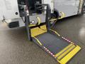 A lowered wheelchair ramp extending from the back of a 2018 Chevrolet Express designed for accessibility with yellow safety markings and a sturdy metal frame