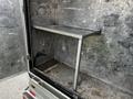 A 2007 Ford F-550 with an empty cargo area featuring a metal shelf installed on one side