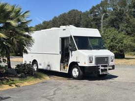 A white 2019 Freightliner MT45 step van with a large opening on the side for access, featuring a boxy design and large front windows