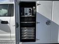 A 2018 Ford F-550 with an open utility cabinet displaying various tools and equipment inside