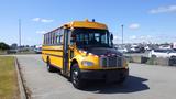 A 2014 Freightliner Thomas Diesel school bus with a bright yellow exterior black tires and a red and white reflective stripe along the front hood