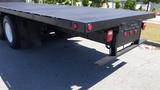 A black 2017 Freightliner M2 106 flatbed truck with red lights on the rear and a textured surface on the flatbed