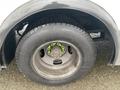 A close-up view of a tire mounted on a metallic wheel of a 2012 Chevrolet Express with distinctive green lug nuts visible on the wheel