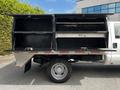 A 2016 Ford F-550 truck with an open utility bed featuring black storage compartments on both sides and a silver exterior