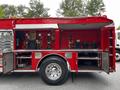 A red 1991 Sutphen Deluge fire truck with open compartments displaying various firefighting equipment and gear inside the storage area
