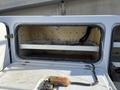 A 2015 Ford F-450 SD with an open tool compartment showing bare wood shelves and mounting points without any tools or equipment inside