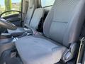 Interior view of the front seats of a 2012 Isuzu NPR HD showing two gray fabric seats with seatbelts and armrests