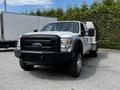 A 2016 Ford F-550 with a black front grille and a utility bed in the back, positioned in the foreground with large tires and high clearance