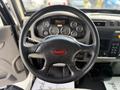 Steering wheel of a 2015 Peterbilt 337 showing the logo and assorted gauges in the dashboard area